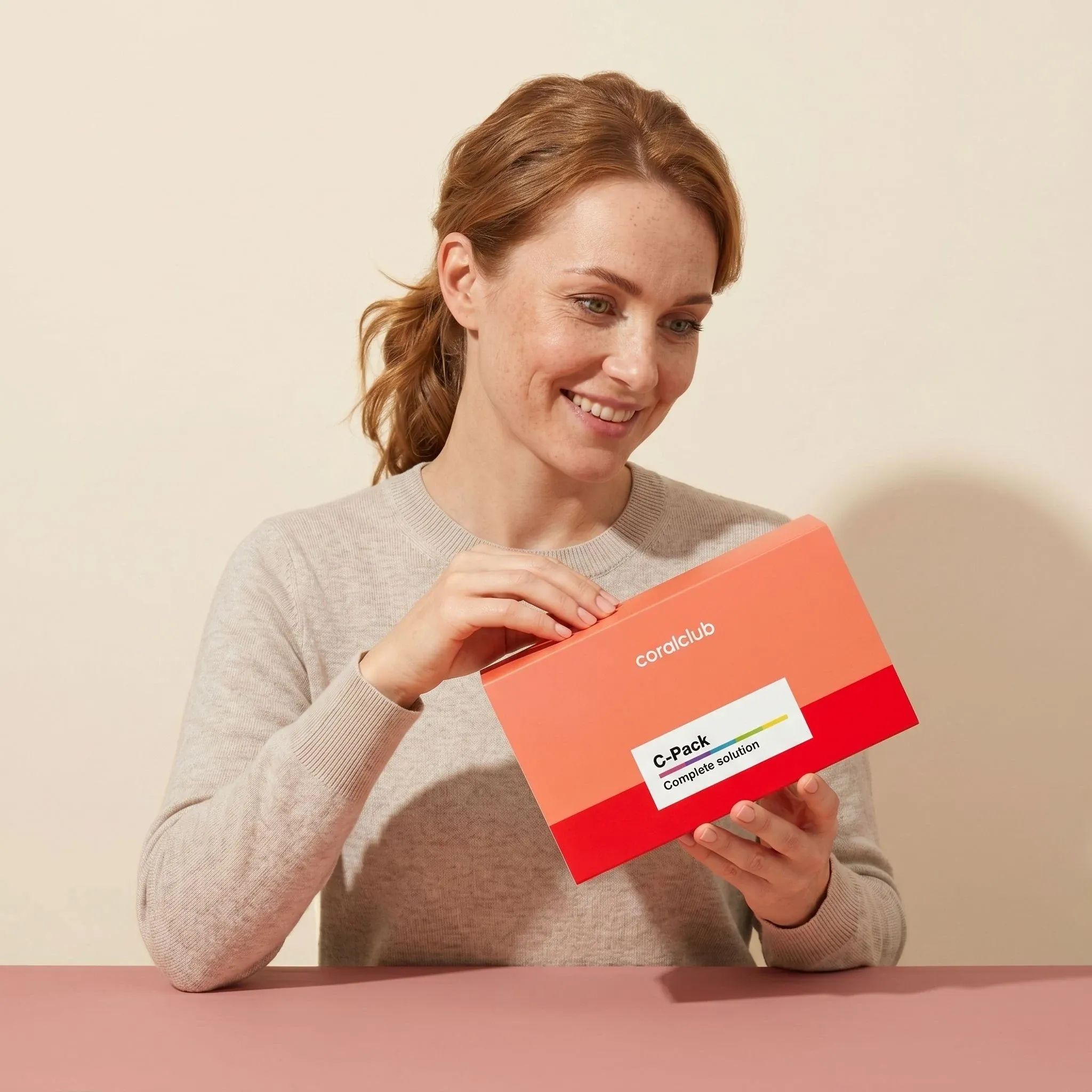 Woman opening C-Pack box in a lifestyle setting, showcasing the product's packaging and vibrant colors.