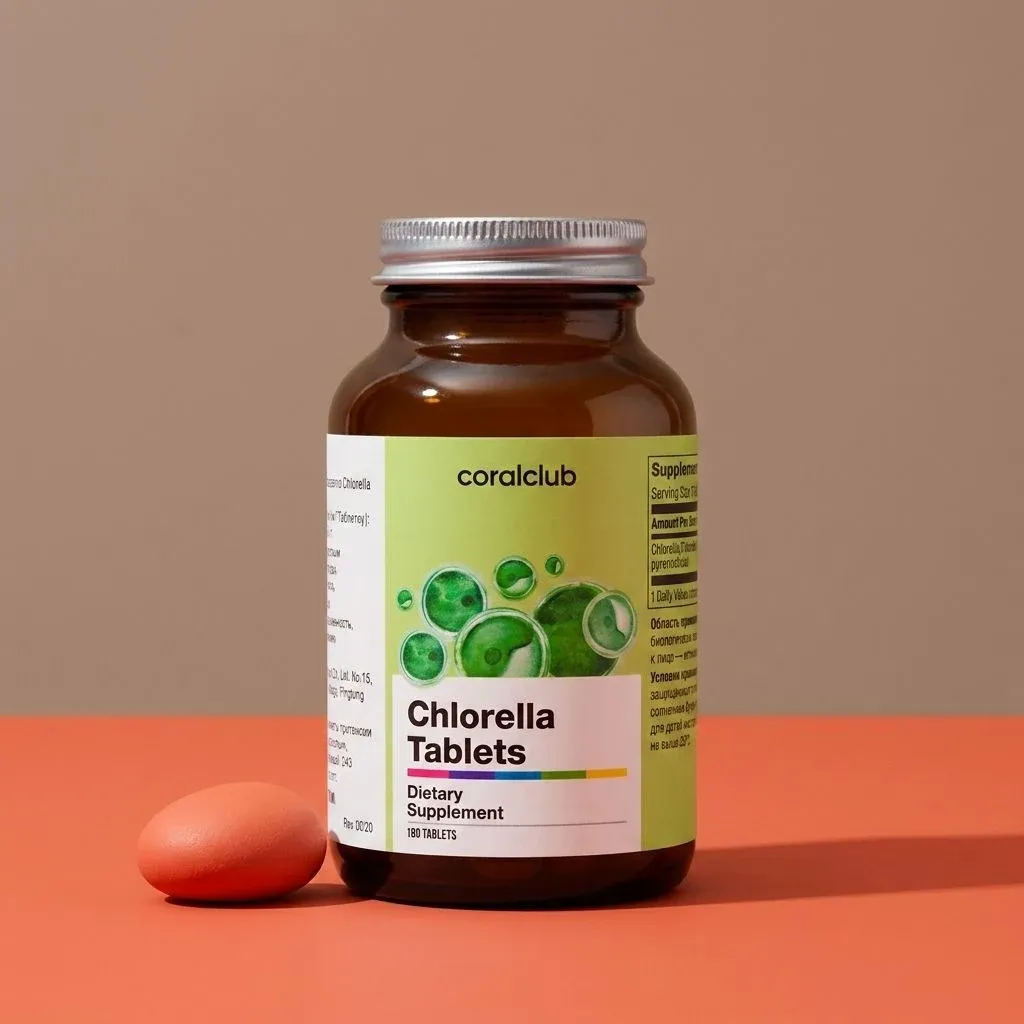 Chlorella Tablets packshot in a brown bottle with green label and orange tablet on a coral background.