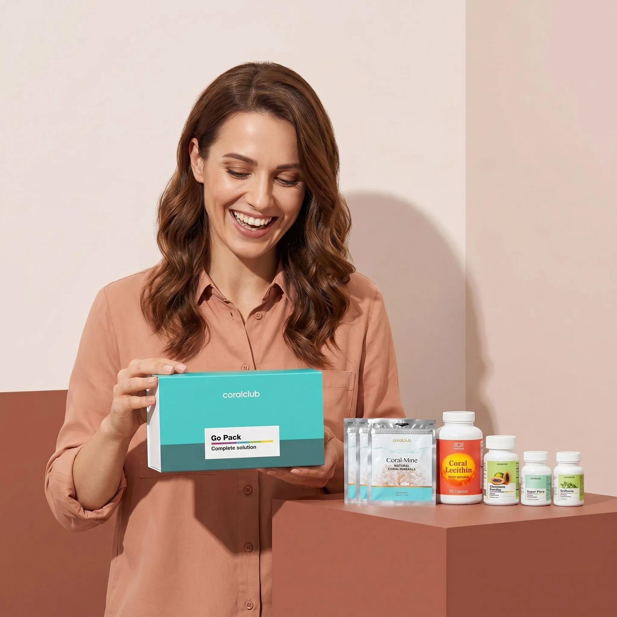 Healthy Start Pack lifestyle image featuring a woman happily holding the product box with various supplements displayed.
