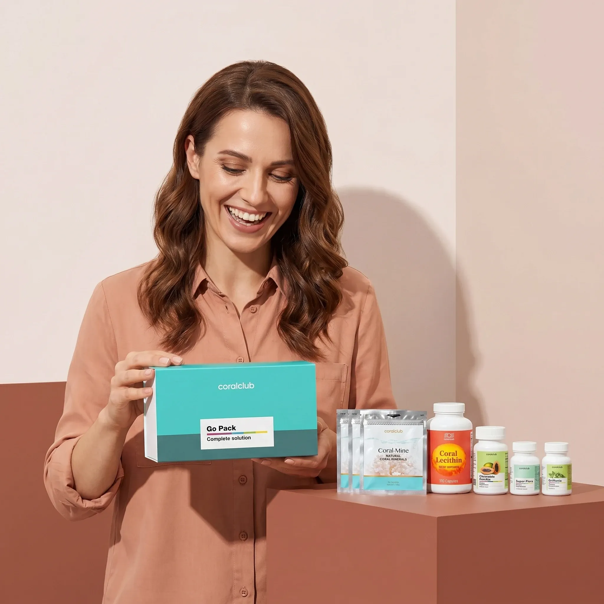 Healthy Start Pack lifestyle image featuring a woman happily holding the product box with various supplements displayed.