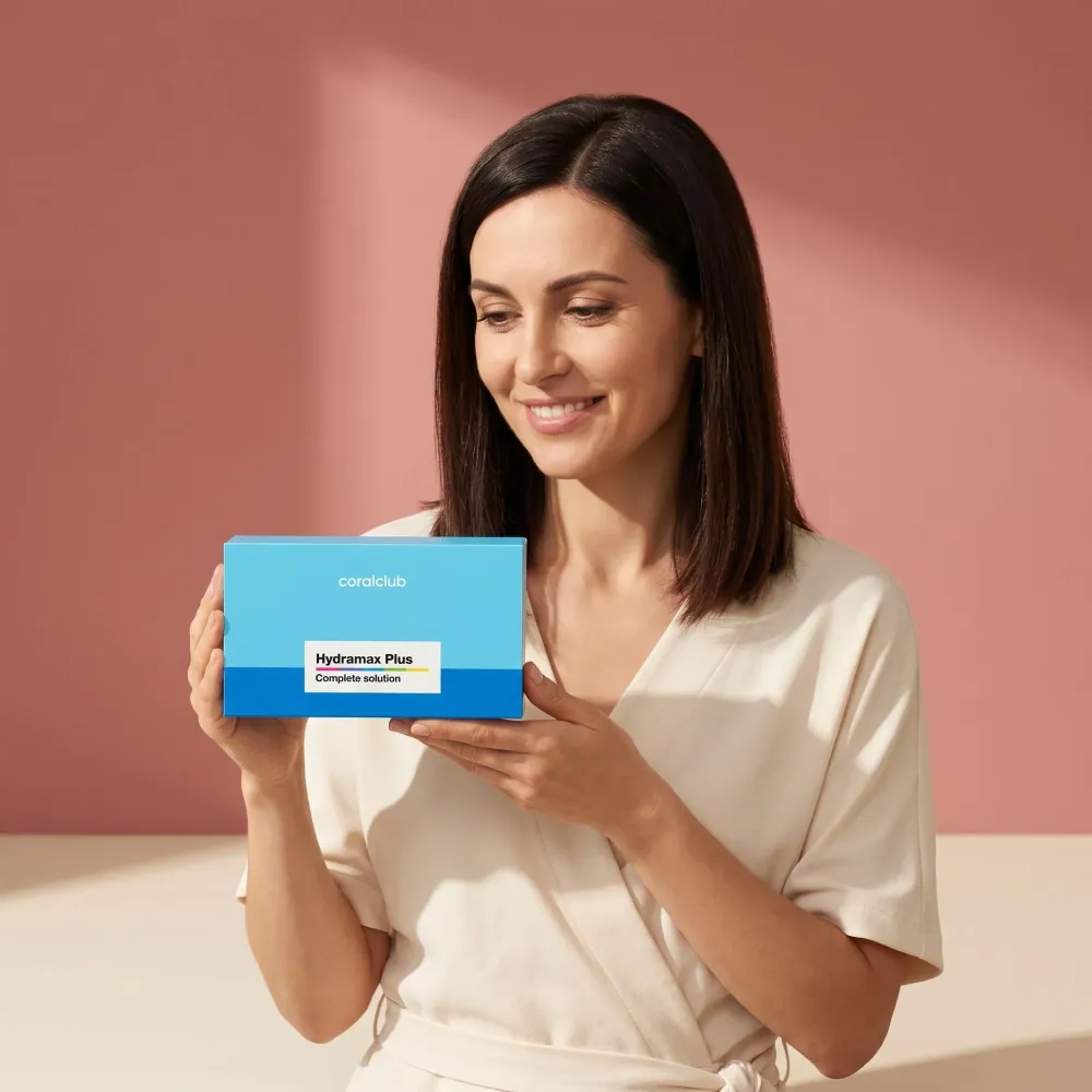 Woman holding HydraMax Plus box in a lifestyle setting with a soft pink background.