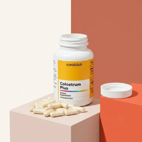 Colostrum Plus dietary supplement bottle with capsules on a pastel background.