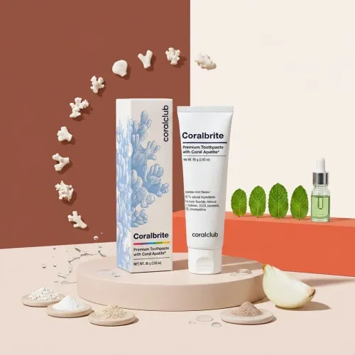 Coralbrite toothpaste with coral calcium, surrounded by natural ingredients like mint and onion.